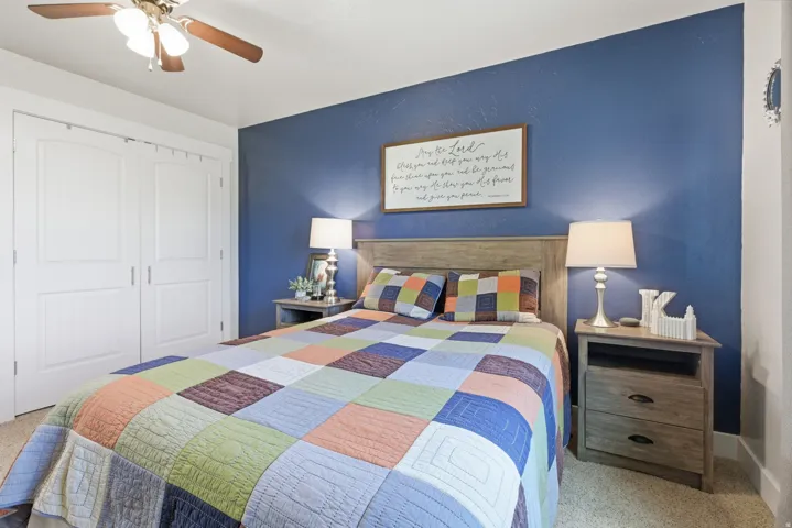 Bedroom featuring a prominent accent wall, textured carpeting, and a ceiling fan with integrated lighting