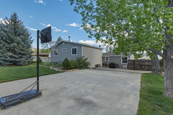 Expansive concrete driveway with surrounding mature trees and a manicured lawn