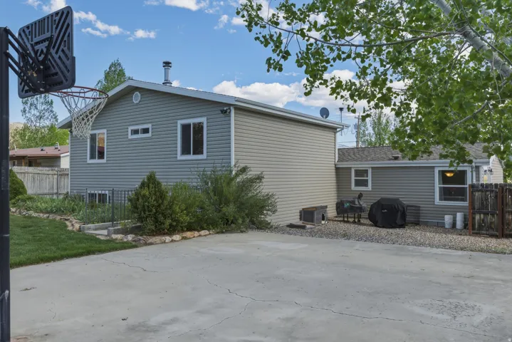 Rear exterior featuring gray siding, white trim windows, and a concrete patio