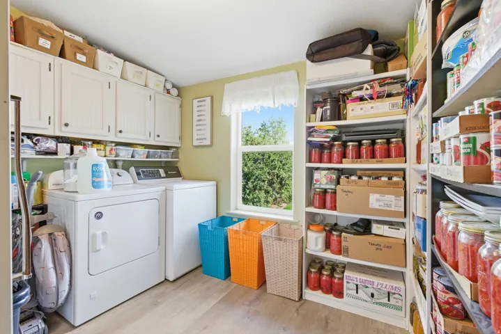 Dedicated utility room featuring light wood-finish flooring, ample built-in cabinetry, and integrated shelving