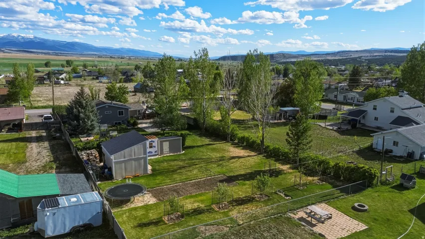 Expansive green space featuring a large residential lot, mature trees, and a mountain backdrop