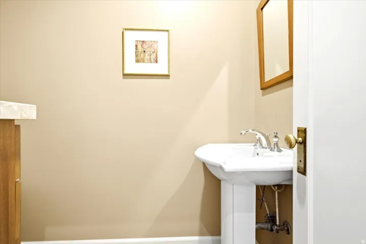 Pedestal sink with chrome fixtures and brass door hardware