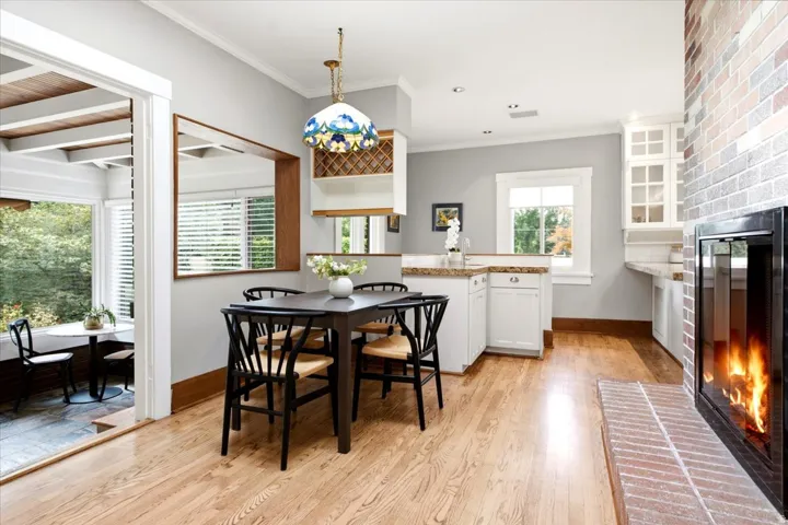 Hardwood flooring throughout, brick fireplace, built-in wine rack, white cabinetry, and granite countertops