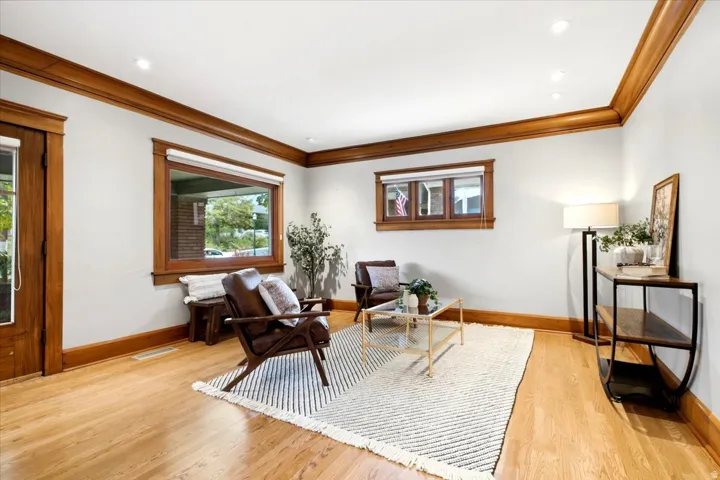 Hardwood flooring, crown molding, recessed lighting, wood-framed windows, and a wood-paneled door