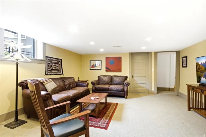Spacious room featuring light-colored carpet flooring, recessed lighting, and a window with security bars