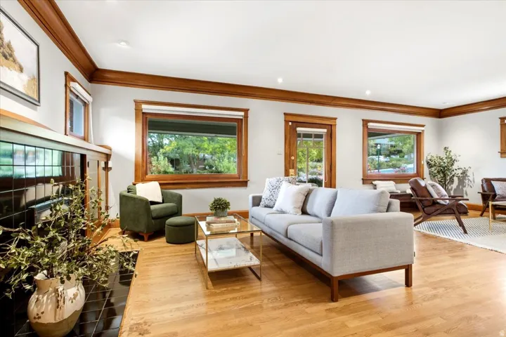 Hardwood flooring with a glossy finish, black tiled fireplace, wood-framed windows, wood-trimmed ceiling, and a wood-framed door