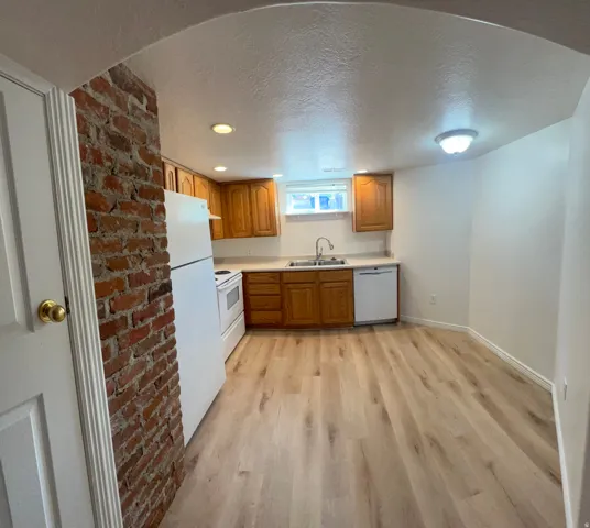 Kitchen with light wood-like LVP flooring, wood cabinetry, and white appliances