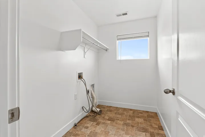 Utility room featuring a window, built-in shelving with hanging rod, and durable patterned flooring