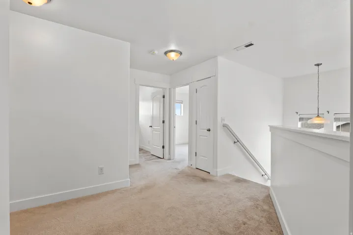 Carpeted hallway featuring white walls and baseboards, two flush-mount ceiling lights, and multiple white doors