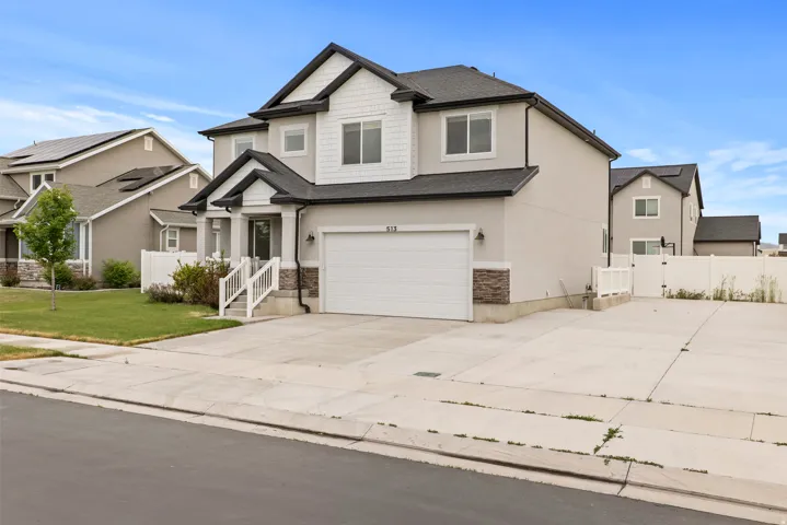 Two-story residence featuring light-colored stucco siding with dark trim accents and a contrasting shingle roof
