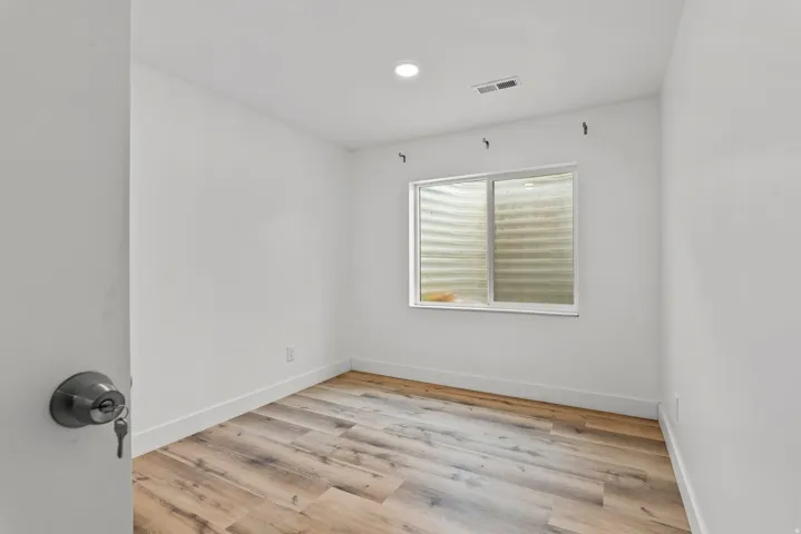 Room featuring wood-finish flooring, white walls, recessed lighting, and a horizontal window