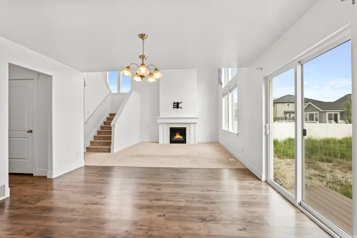 Open-concept living space with wood-finish flooring, a contemporary fireplace, and a large sliding glass door to the exterior