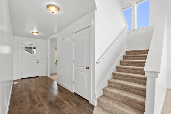 Entryway featuring wood-finish flooring and a carpeted staircase with a white railing