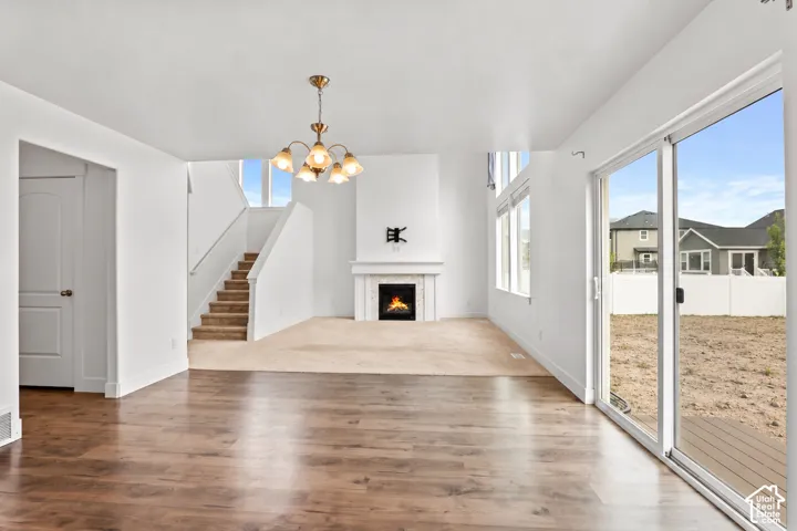 Wood-finish flooring, fireplace with a decorative mantel, chandelier fixture, tall windows, and glass sliding door