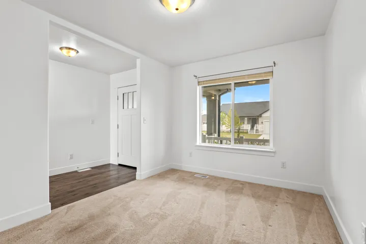 Carpeted interior space featuring a large window with white trim, offering natural light