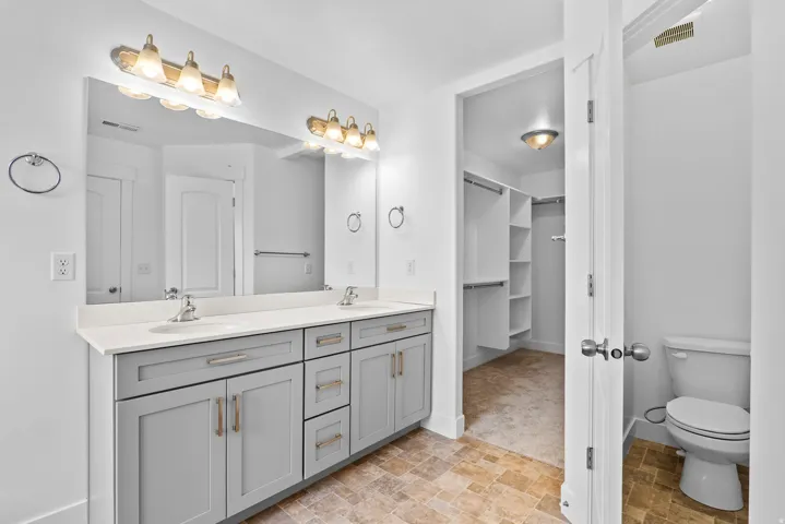 Bathroom featuring a dual vanity with light gray cabinetry, white countertops, and brushed nickel hardware