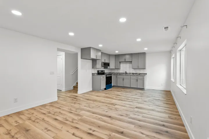 Open-concept living area featuring wood-finish flooring, recessed lighting, and multiple windows