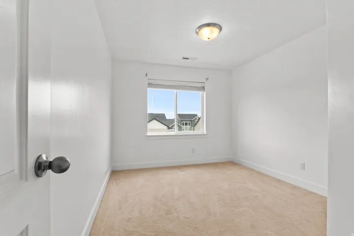 Neutral-toned wall-to-wall carpeting complements the white wall and ceiling finishes