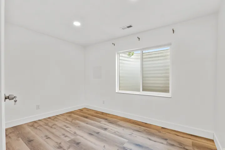 Room featuring wood-finish flooring, white baseboards, and bright white walls