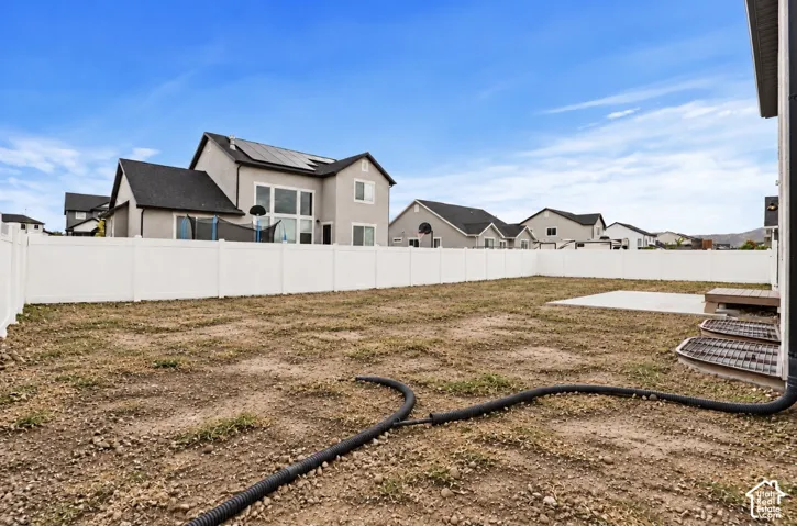 Rear yard featuring a full-perimeter white vinyl privacy fence, concrete patio, and egress window wells