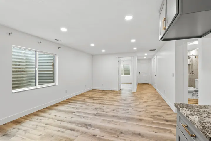 Bright open concept living area featuring recessed lighting, wood-finish flooring, a contemporary window, and white trim