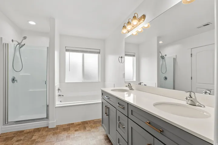 Dual sink vanity with grey cabinetry, white countertop, and chrome fixtures