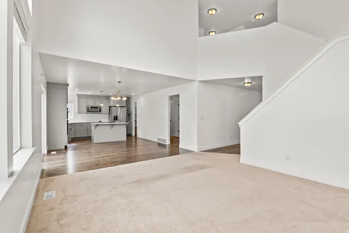 Open-concept interior featuring light-toned carpeting and wood-finish flooring