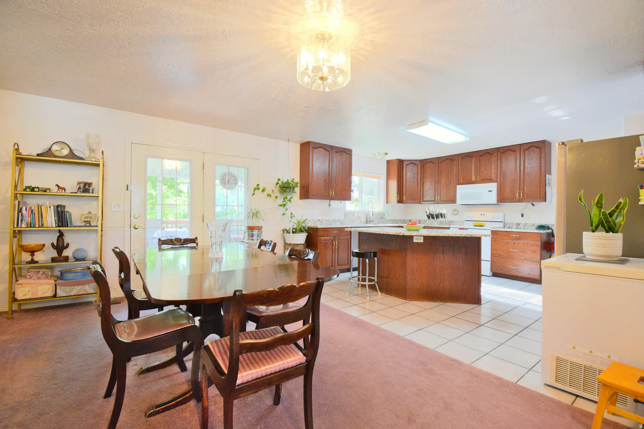 Open-concept kitchen and dining area featuring wood cabinetry, white appliances, and light-toned countertops