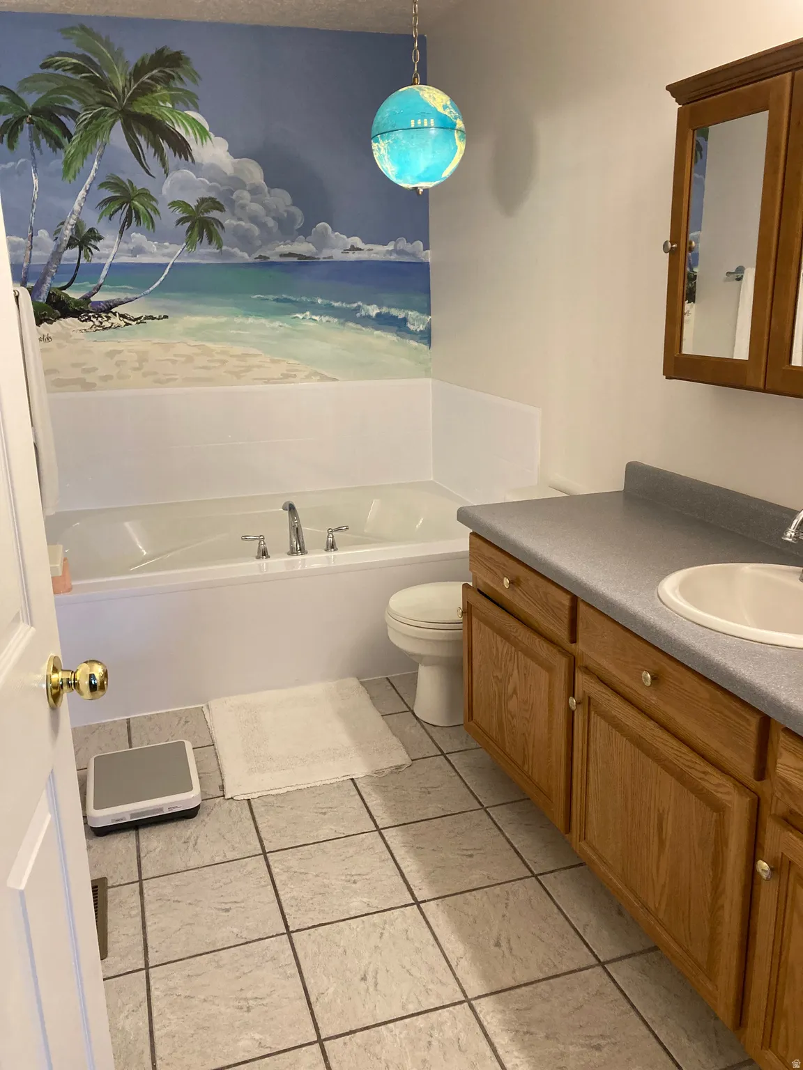 Bathroom featuring a built-in tub, a single vanity with a laminate countertop, oak-finish cabinetry, and square tile flooring