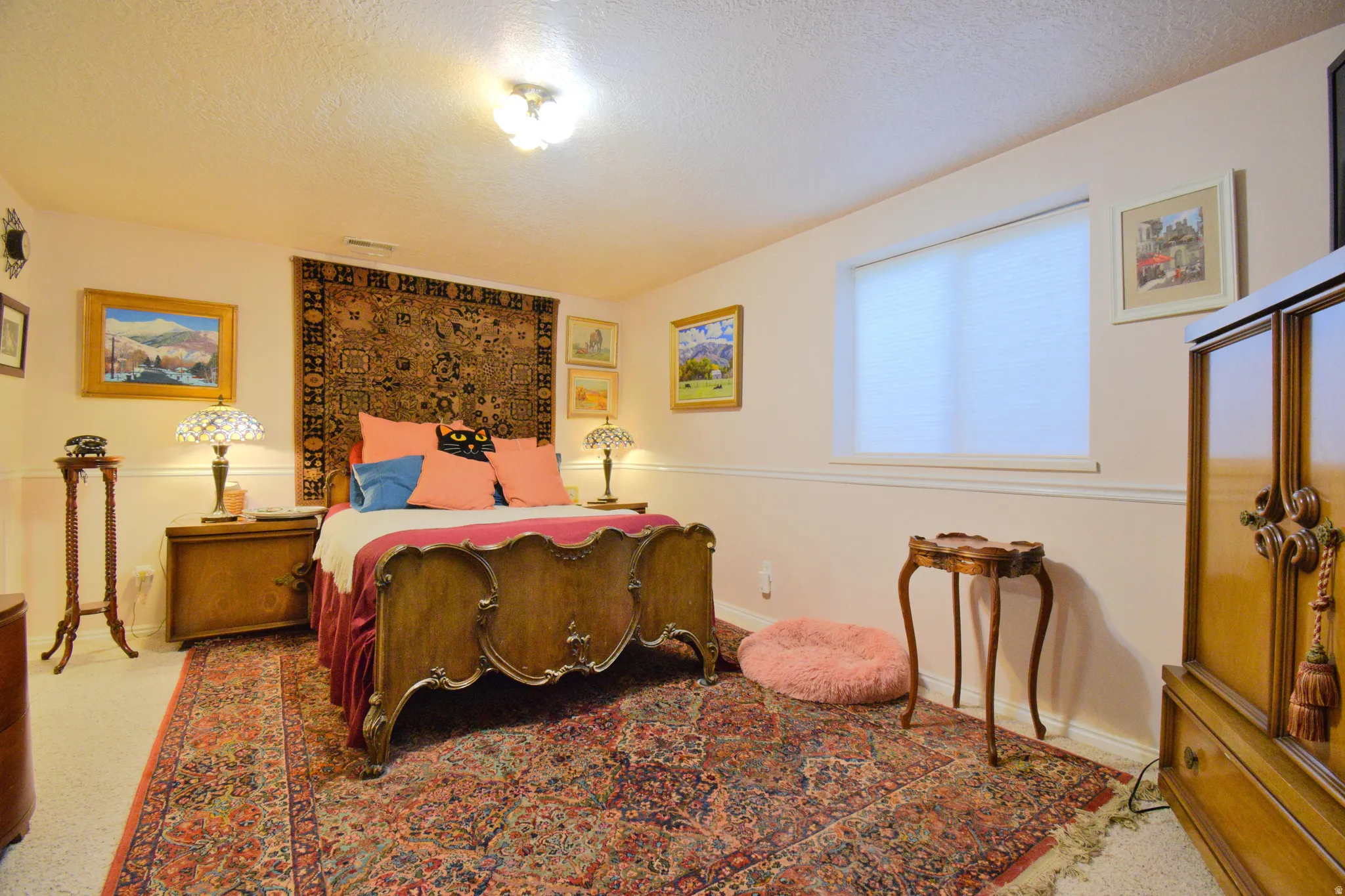 Windowed room with a textured ceiling, painted walls with wainscoting, and carpet flooring