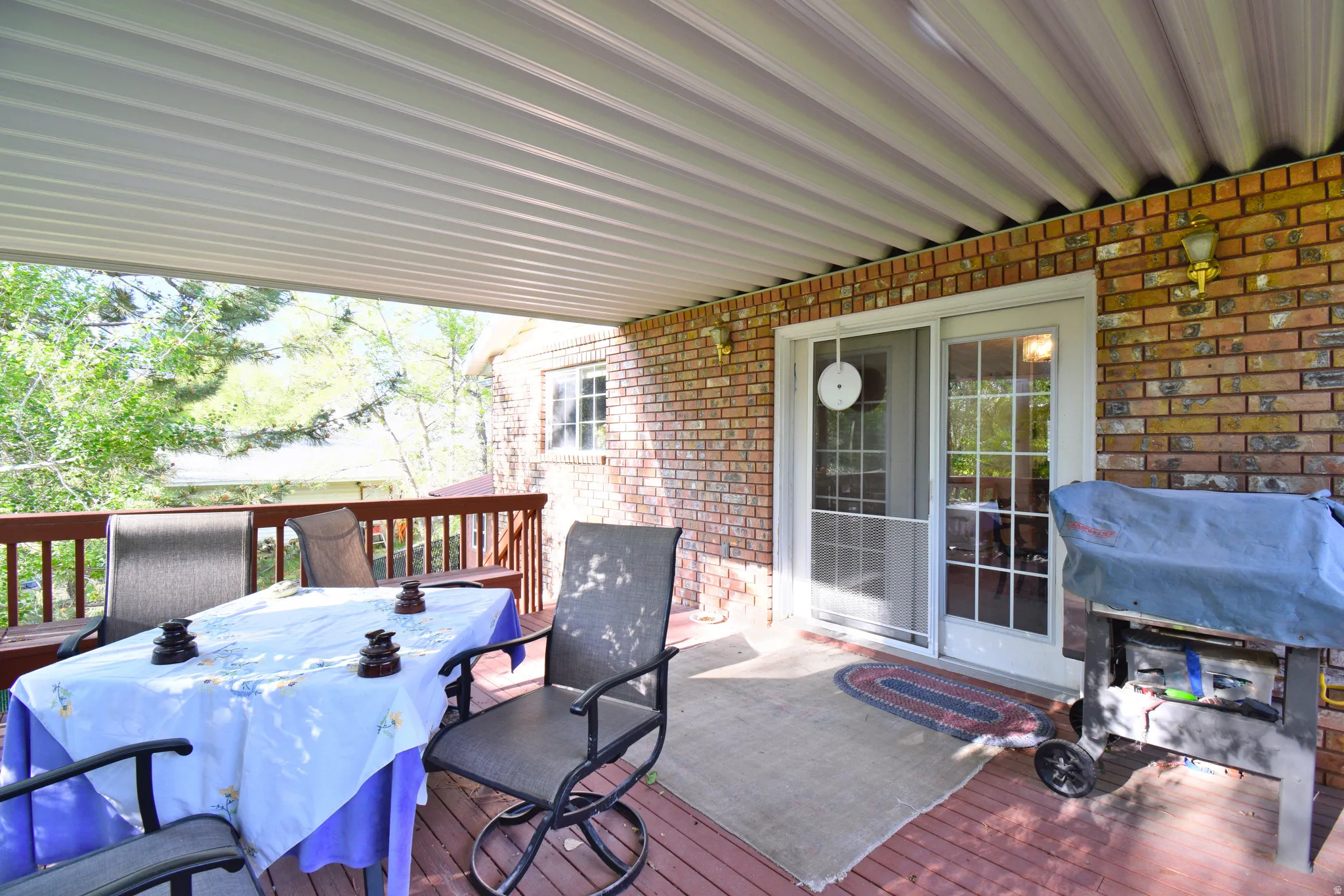 Covered deck area featuring a wood-finish floor and a brick exterior wall