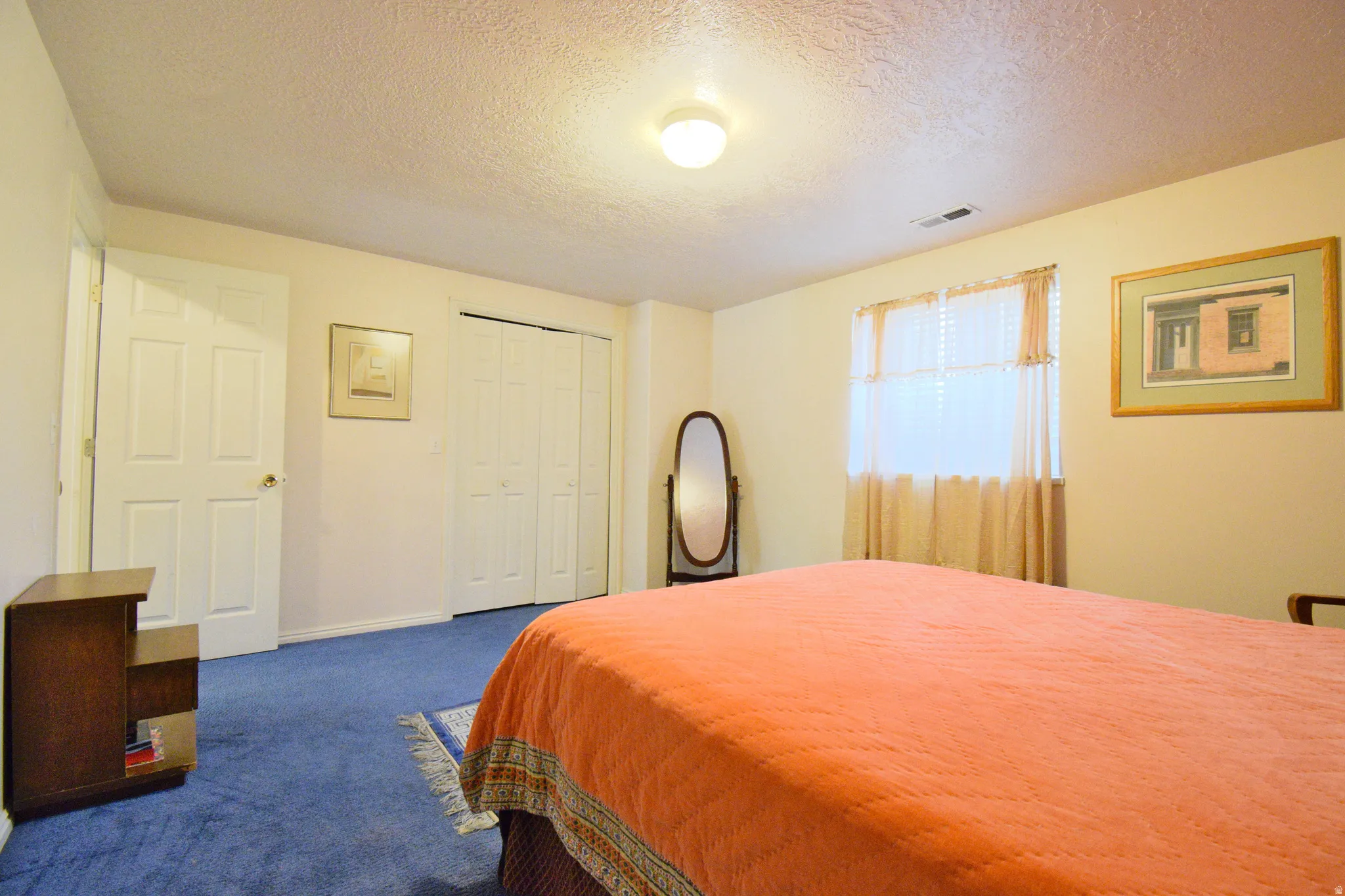 Bedroom featuring blue carpeting, a white two-panel door, and a multi-panel closet door