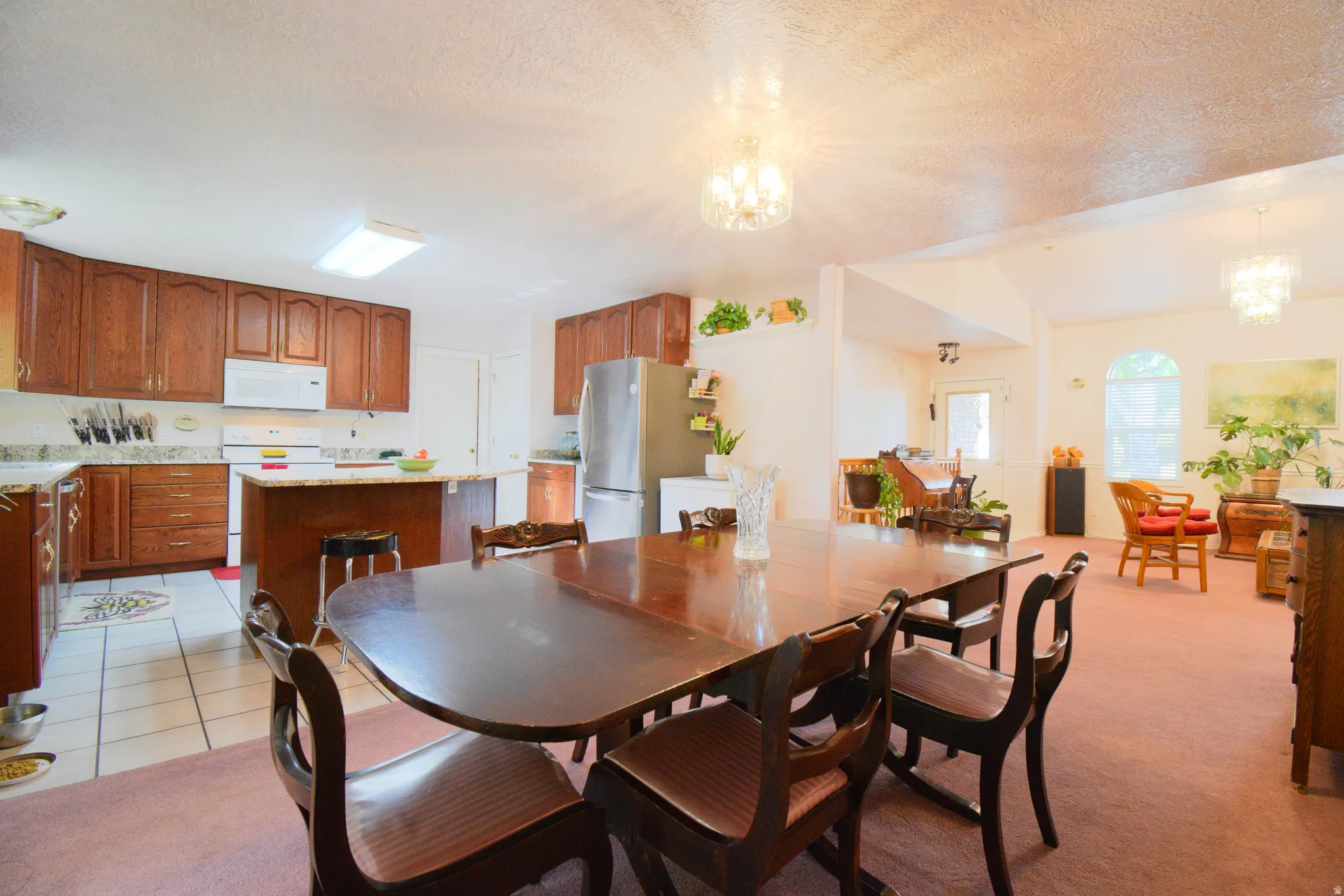 Open-concept living area featuring a kitchen with wood cabinetry, light-toned countertops, and white appliances