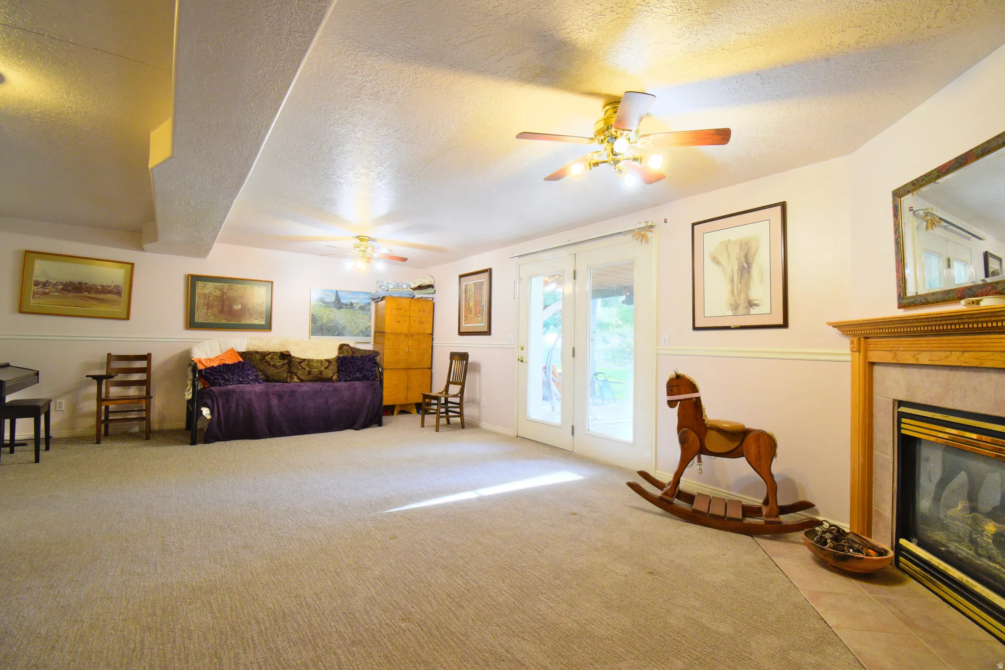 Spacious interior room featuring light-colored carpeting and a built-in fireplace with a wood mantel