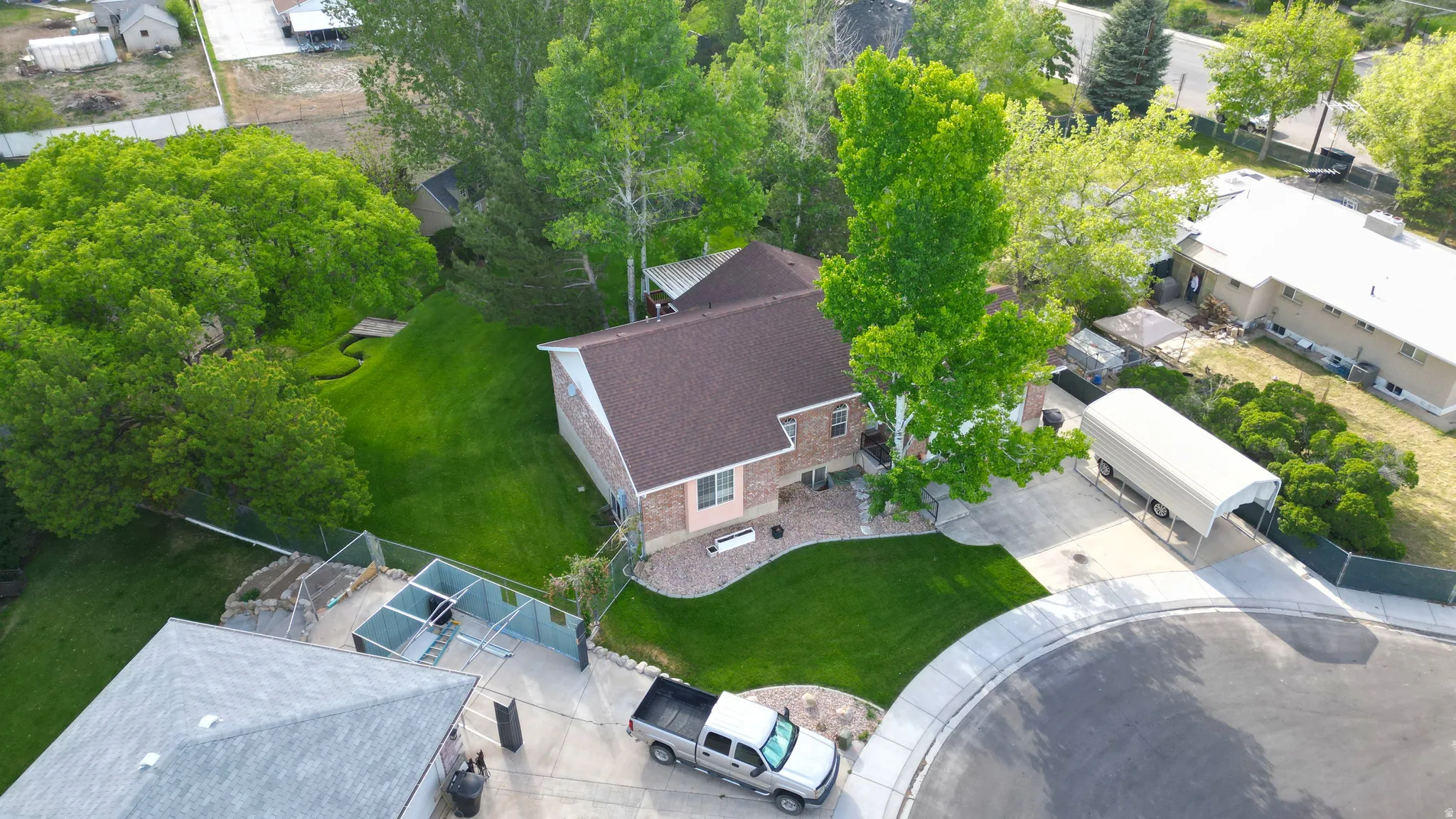 Spacious corner lot featuring a multi-level home with a brown shingle roof and brick siding