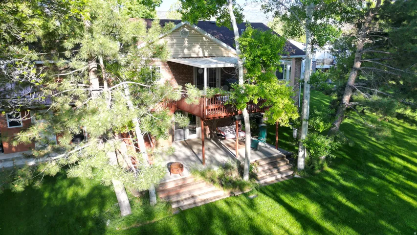Rear exterior featuring a multi-level wood deck, covered patio, and a sloped lawn