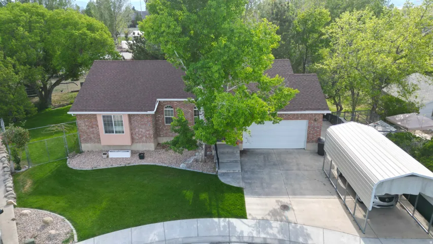 Brick exterior residence with an attached garage, paved driveway, and covered carport