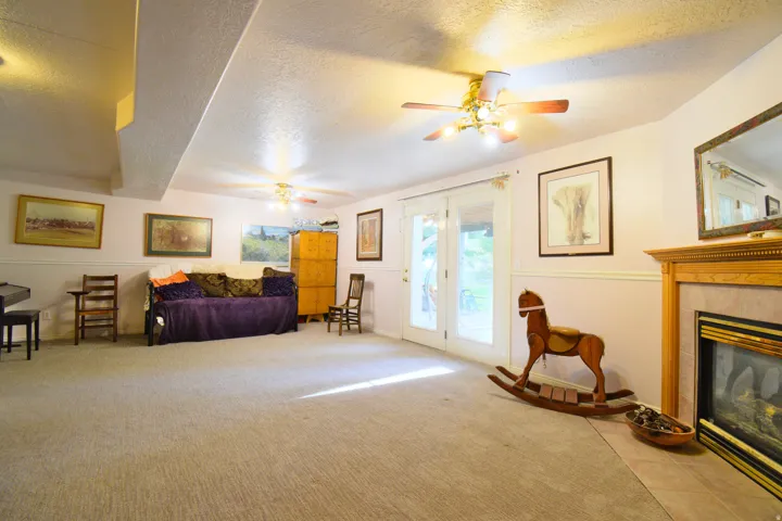 Spacious interior room featuring light-colored carpeting and a built-in fireplace with a wood mantel