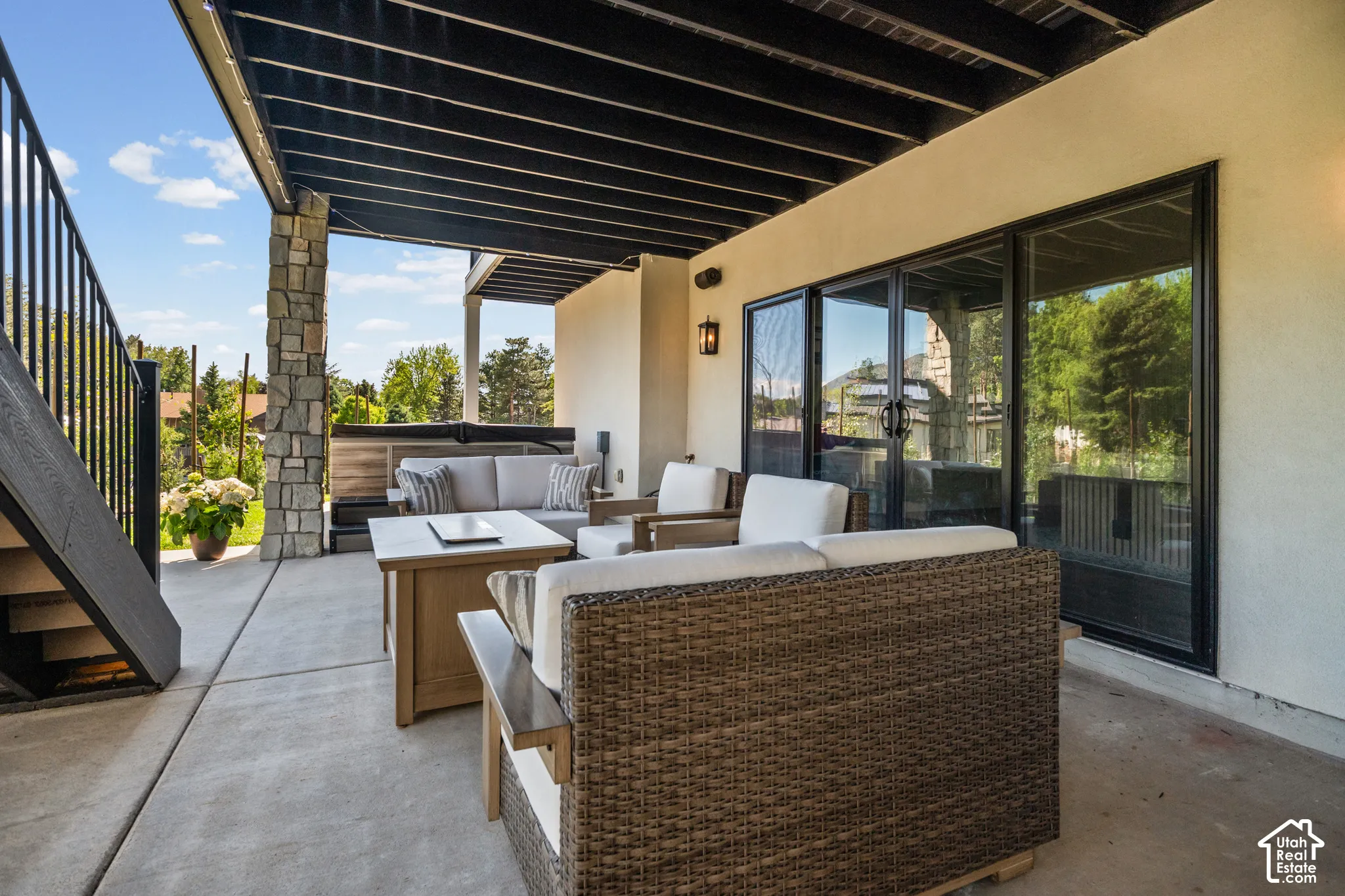 Spacious outdoor patio featuring concrete flooring, a stone-clad pillar, and a stucco exterior wall