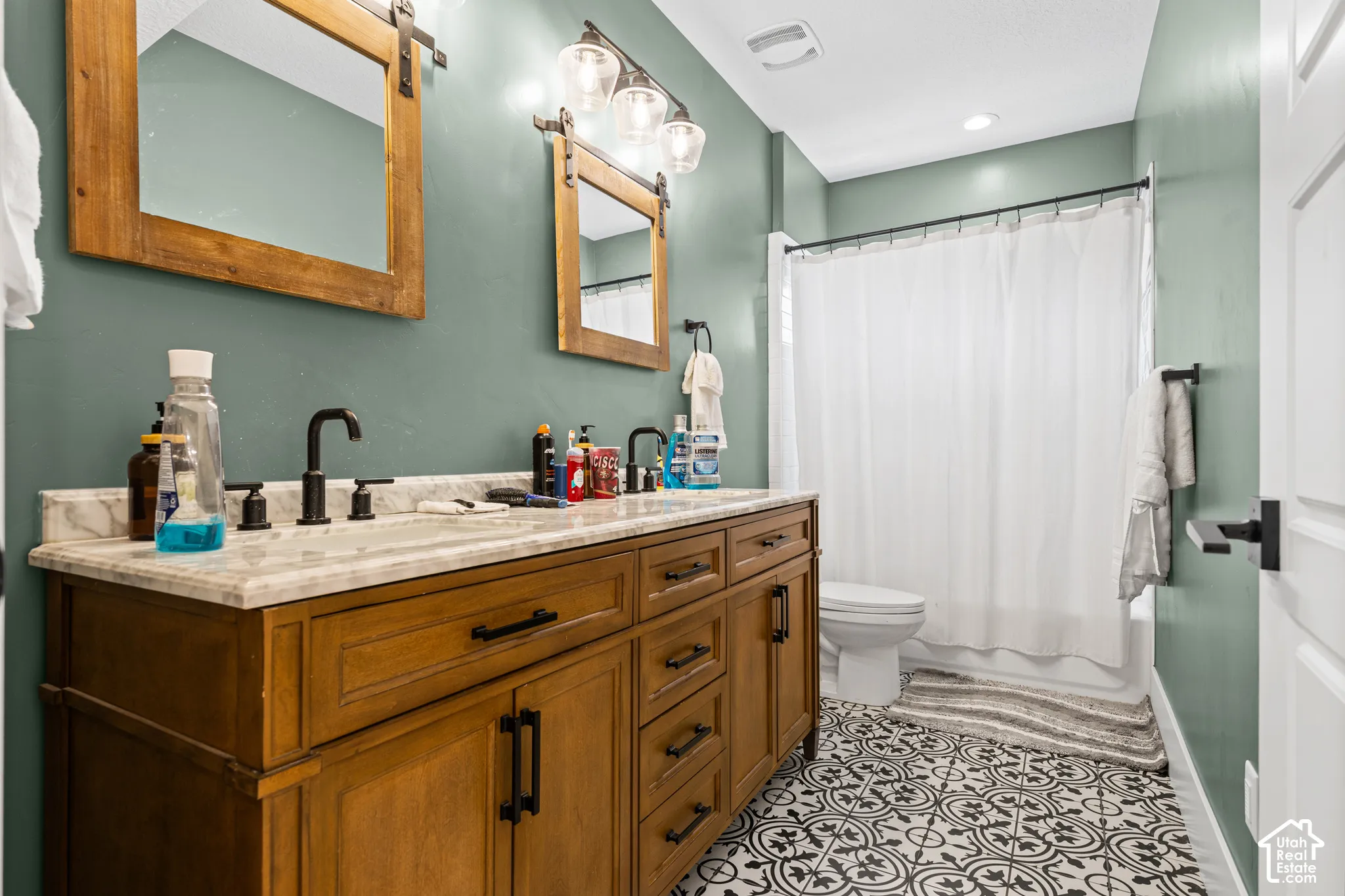 Double vanity featuring a light-colored countertop, wood-finish cabinetry, and black hardware