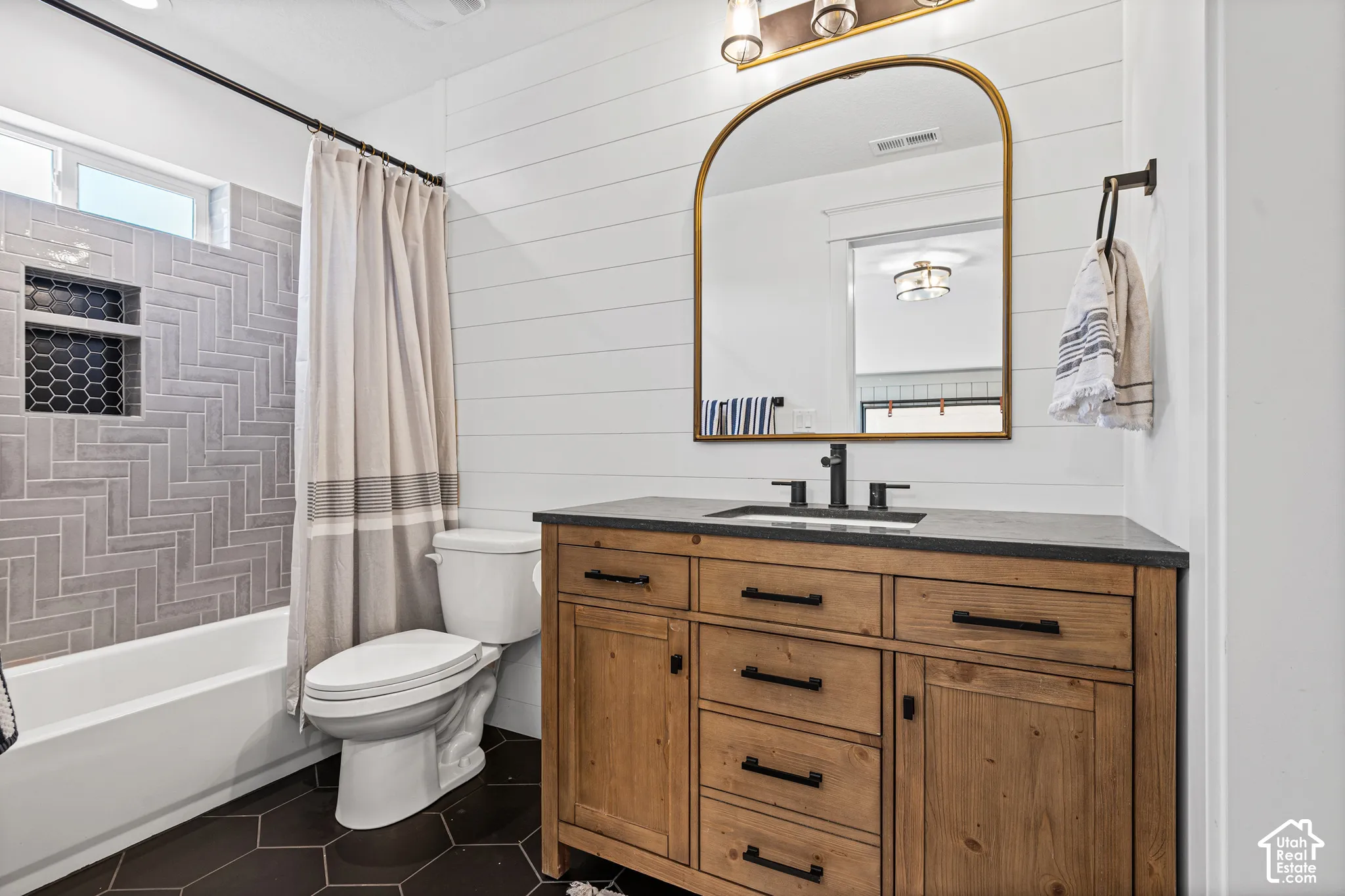 Bathroom featuring a natural wood vanity with black hardware, a rectangular undermount sink, and a dark countertop