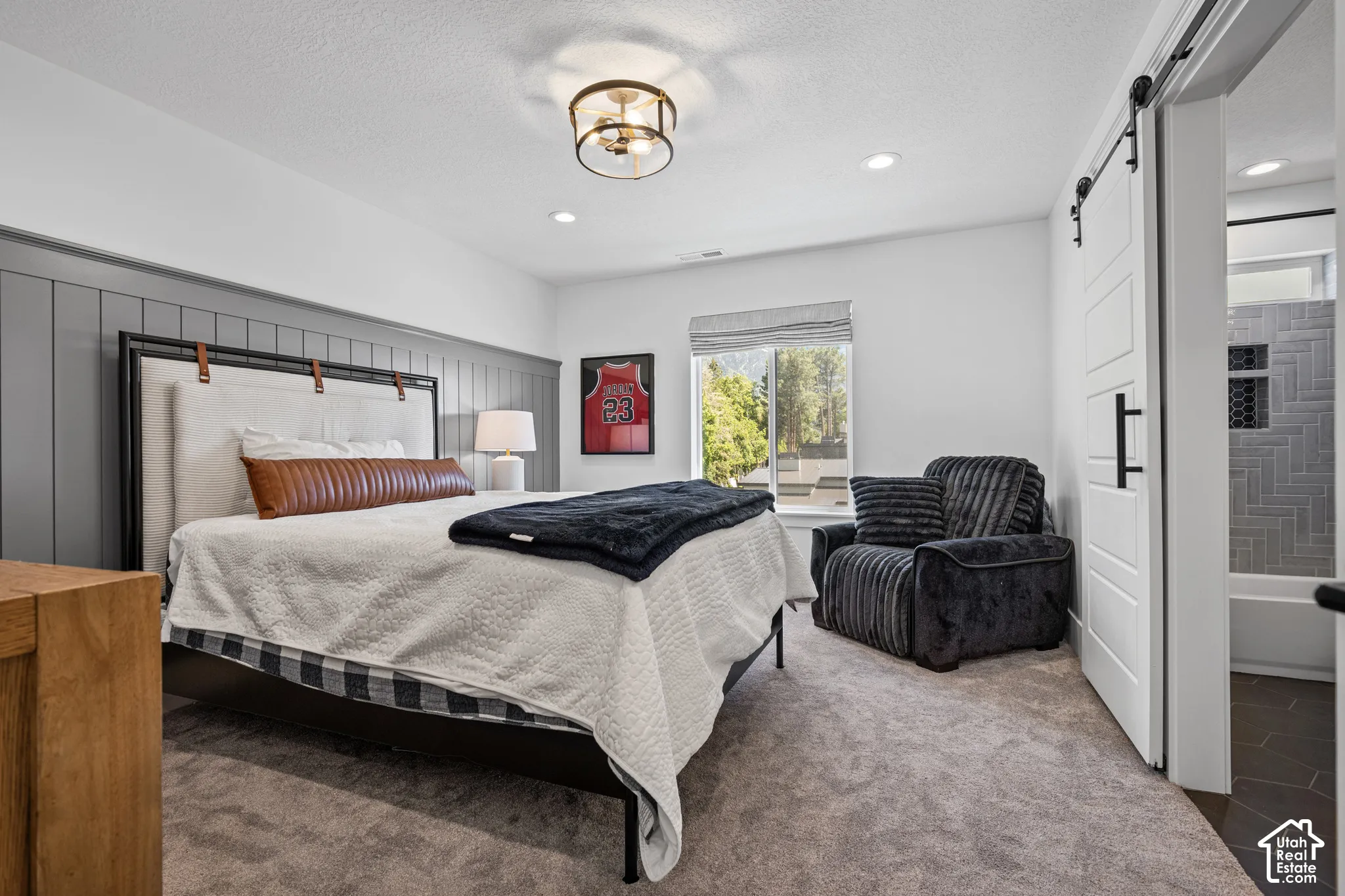Spacious bedroom featuring board and batten accent wall, recessed lighting, and a modern ceiling fixture