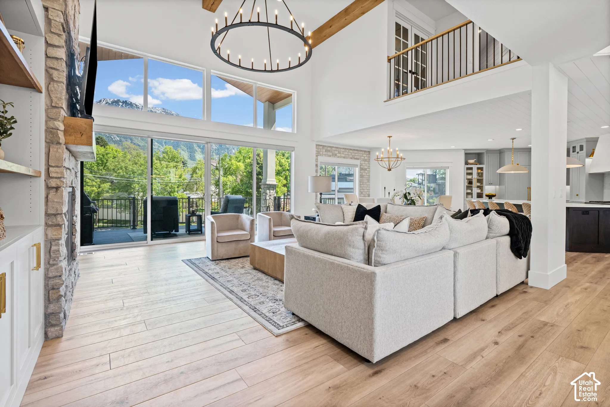 Two-story living area with wood-finish flooring, a stone fireplace, and built-in shelving