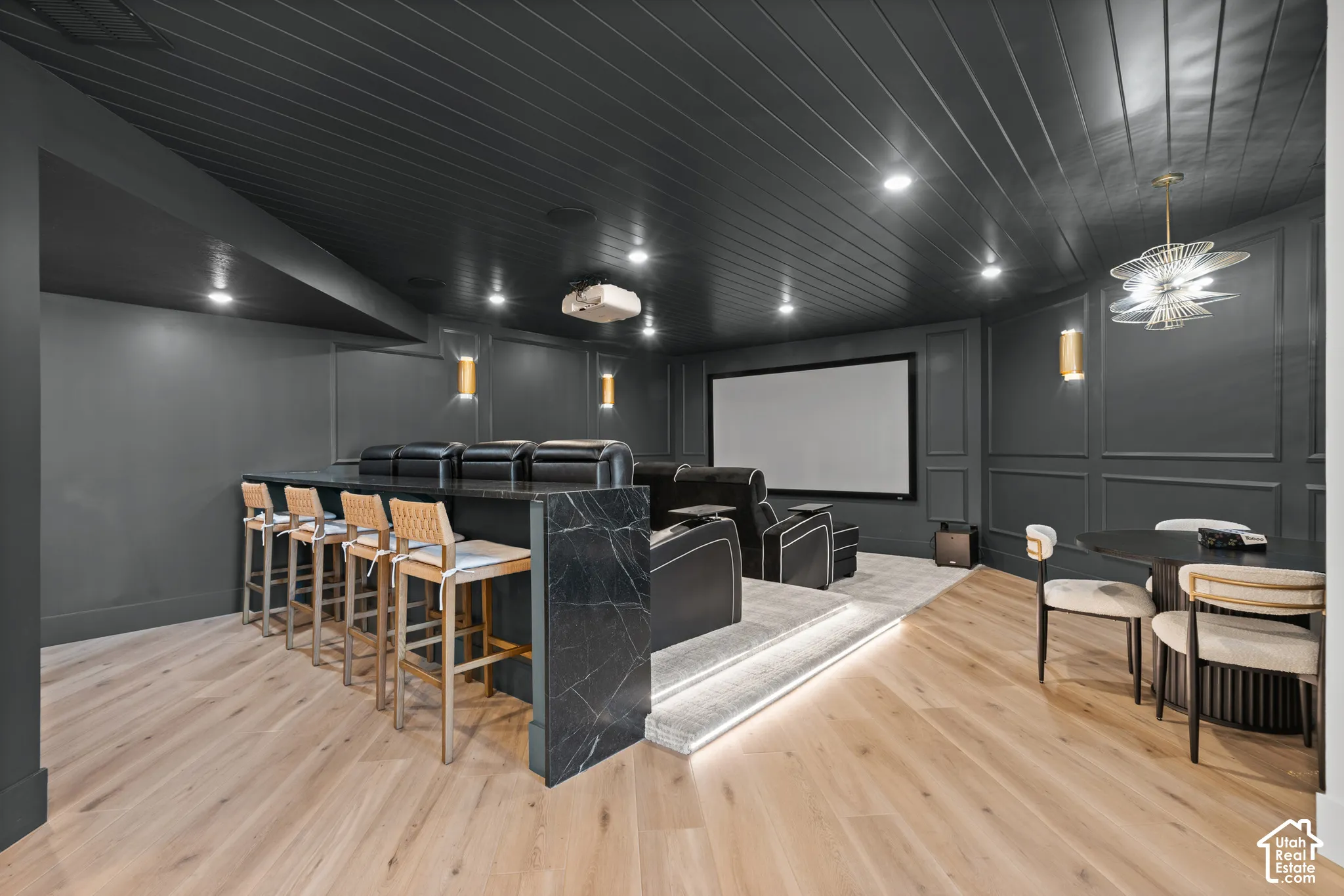 Dedicated home theater featuring a large projection screen, tiered seating, and integrated wall sconces
