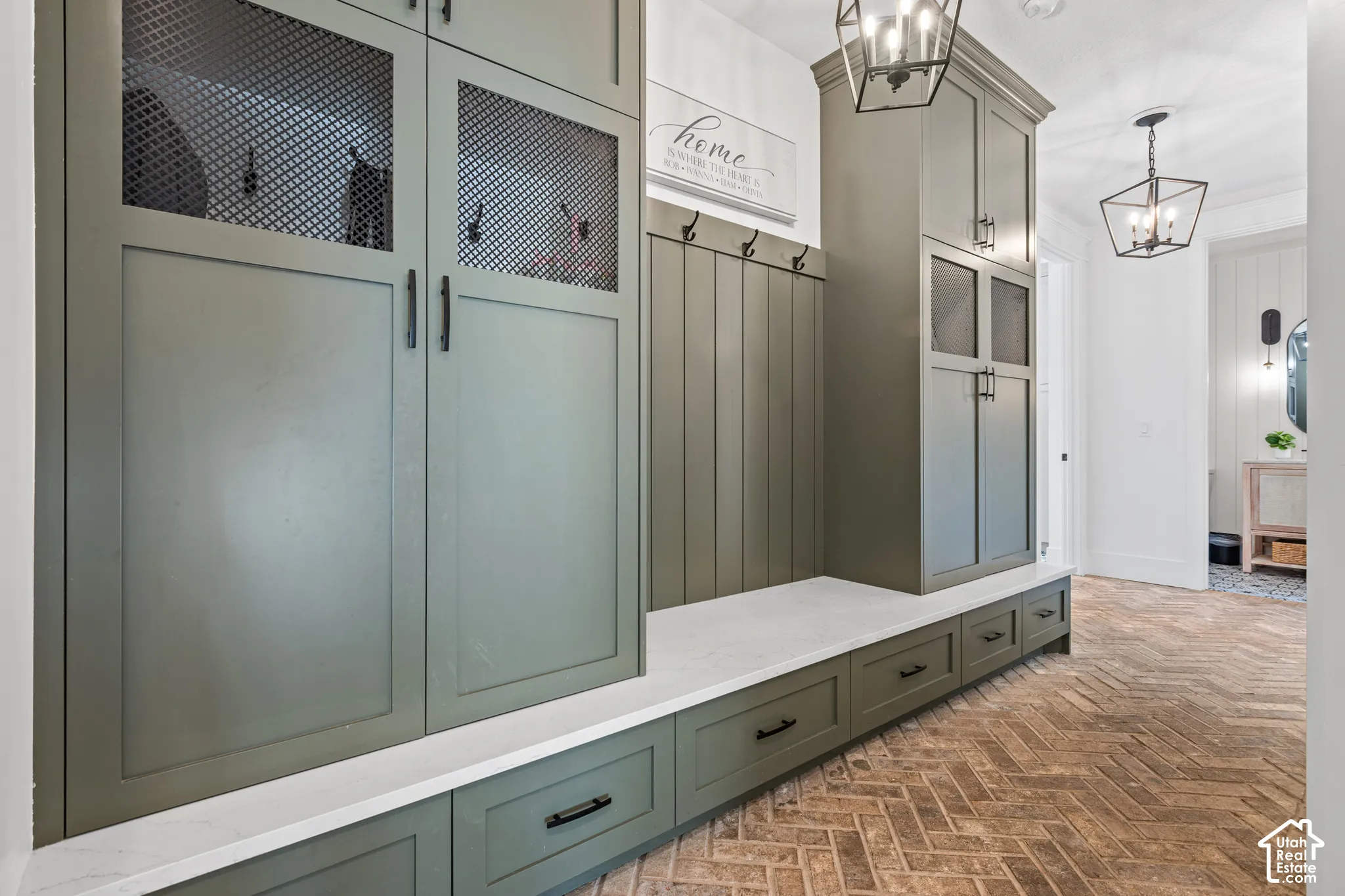 Entryway mudroom featuring built-in cabinetry, integrated bench seating, and herringbone brick-finish flooring