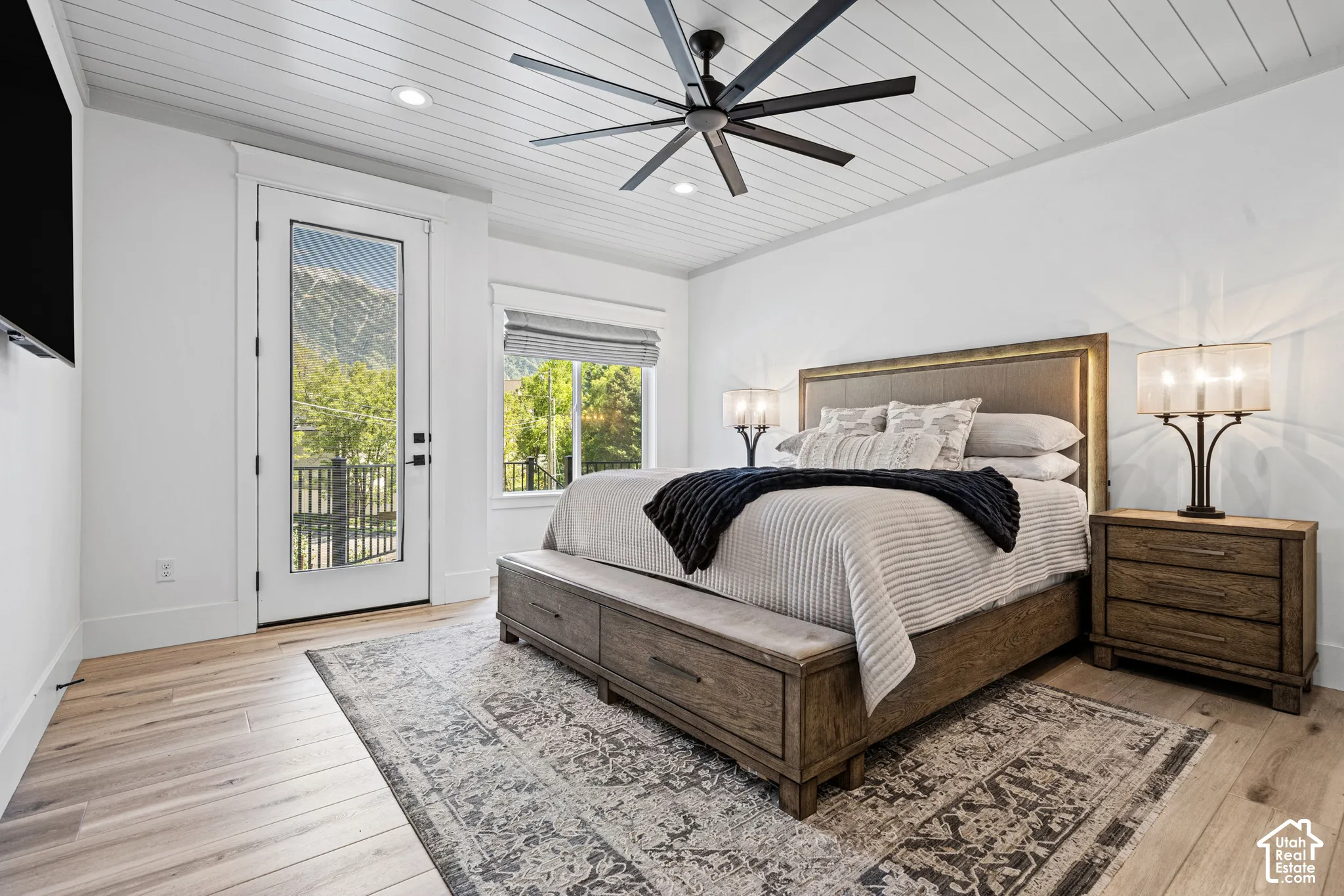 Bedroom featuring light wood-finish flooring and a white shiplap ceiling with a dark-toned ceiling fan