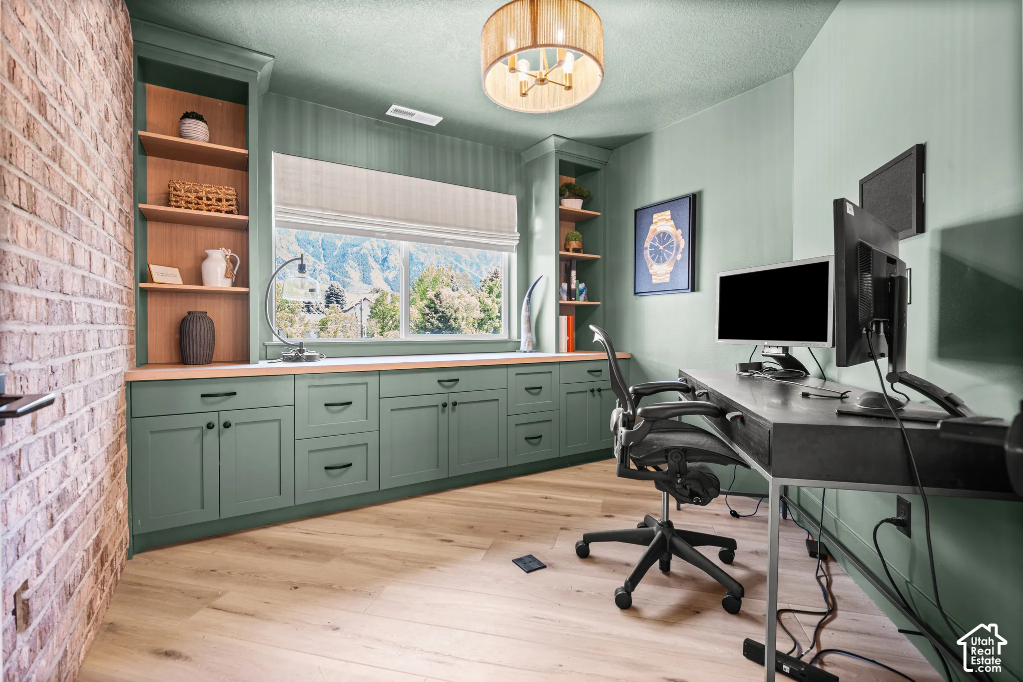 Dedicated office space featuring extensive built-in cabinetry with a natural wood countertop, open shelving, and light wood-finish flooring
