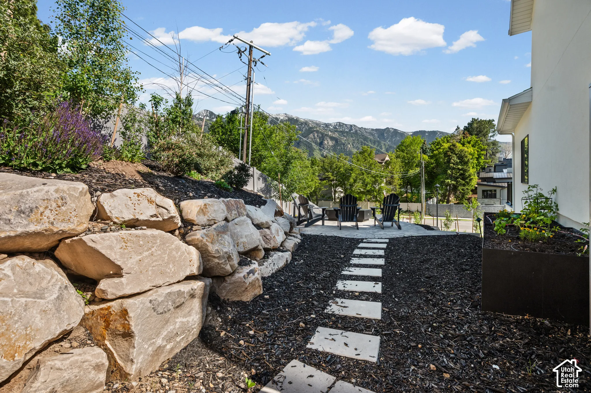 Landscaped exterior featuring a natural stone retaining wall