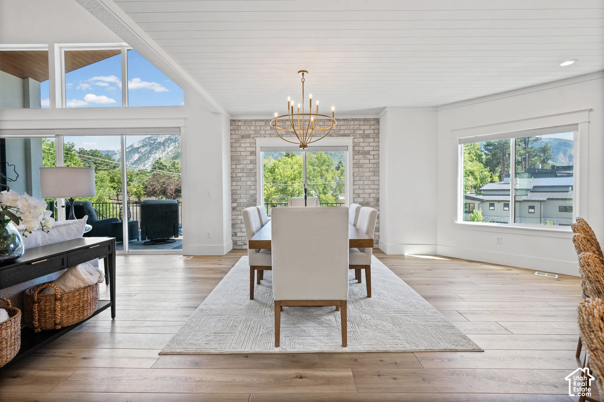 Dining area featuring wood-finish flooring, white shiplap ceiling, and a prominent chandelier