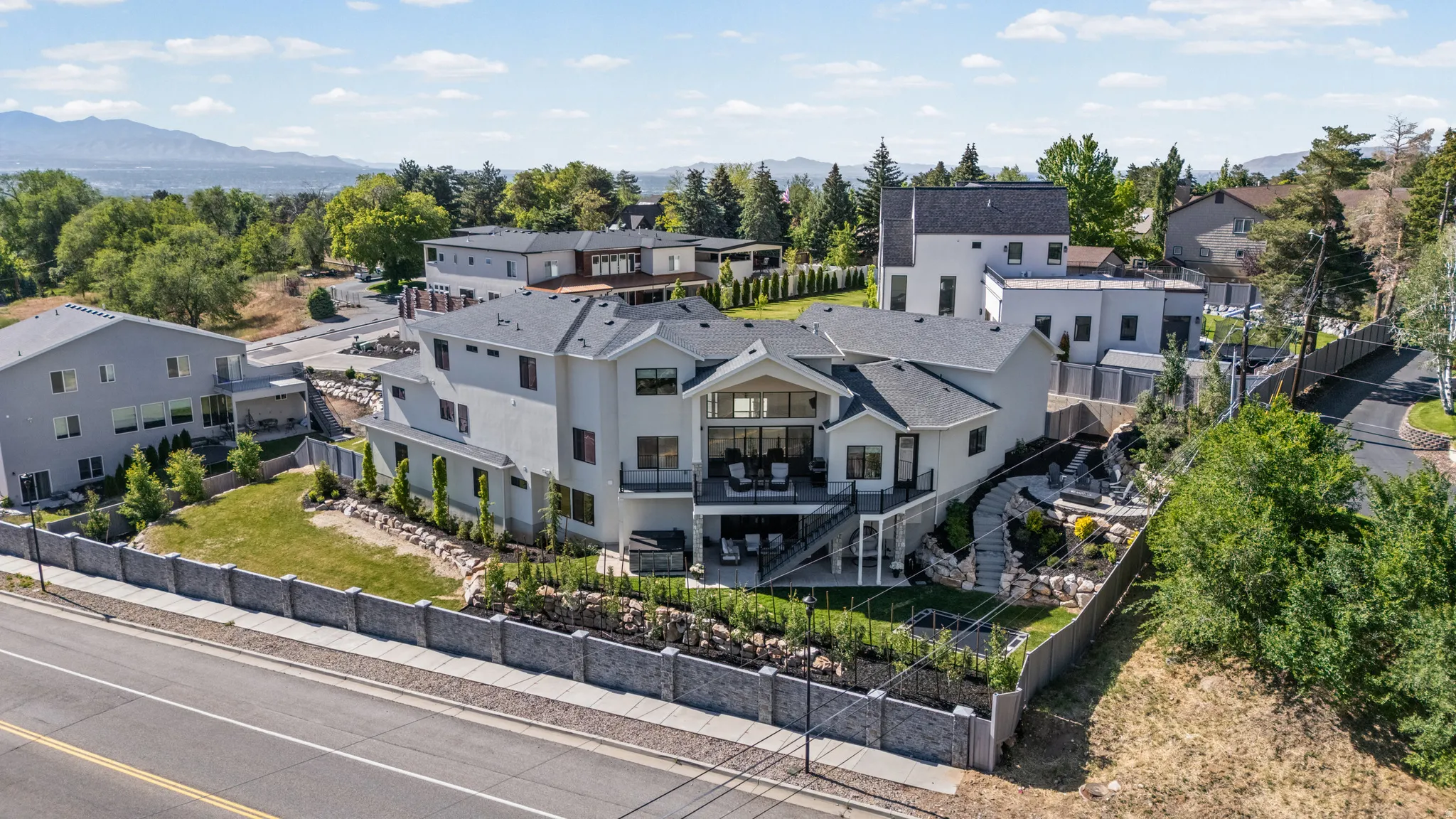 Contemporary multi-level residence featuring stucco exterior, multiple outdoor decks, and a terraced backyard with landscaping